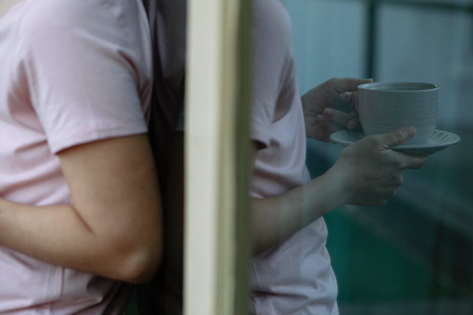 anonymous person leaning on glass door and drinking coffee