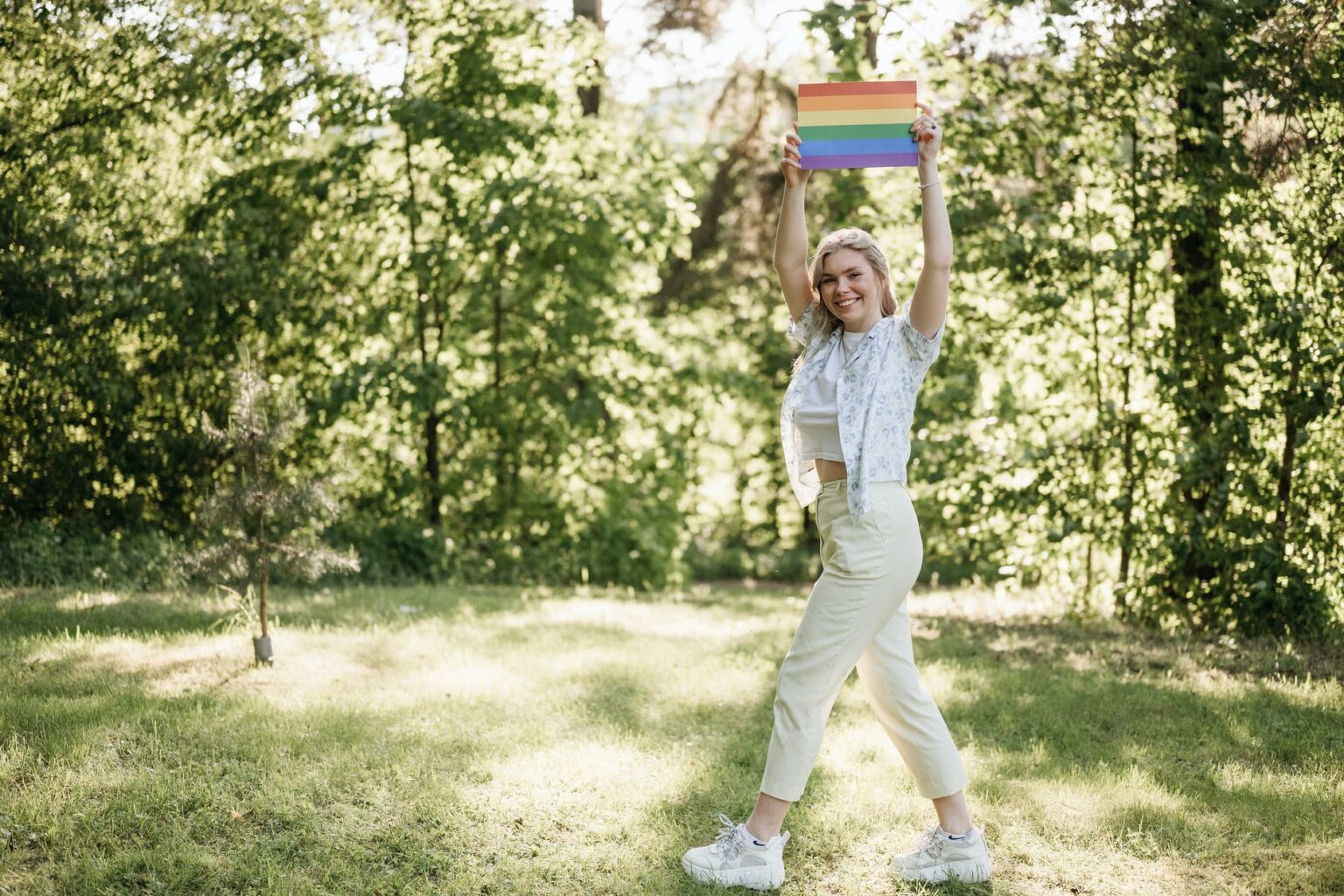 a woman walking while holding a rainbow flag above her head